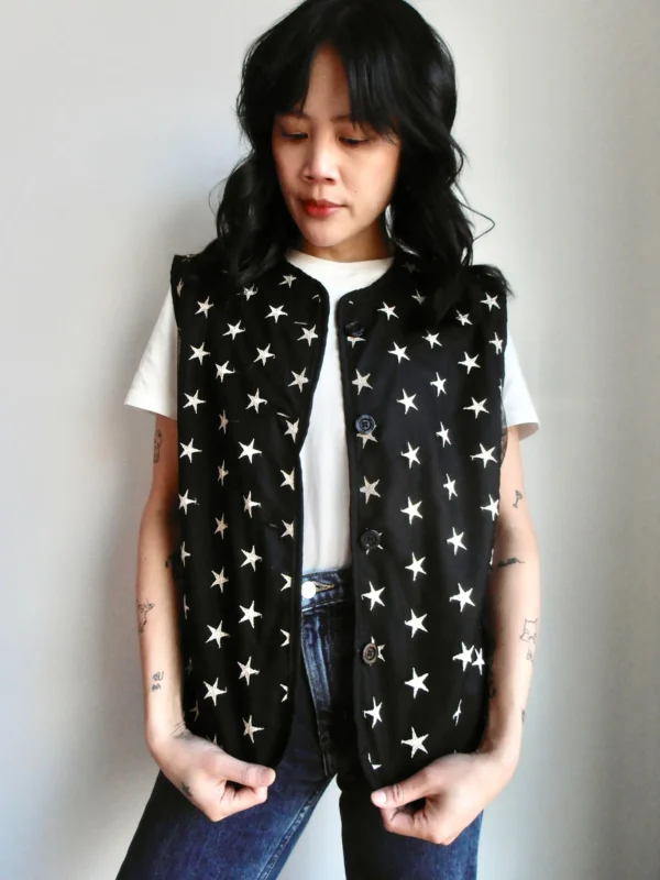 Front view of a black vest with embroidered silver star pattern, made from sustainable materials.