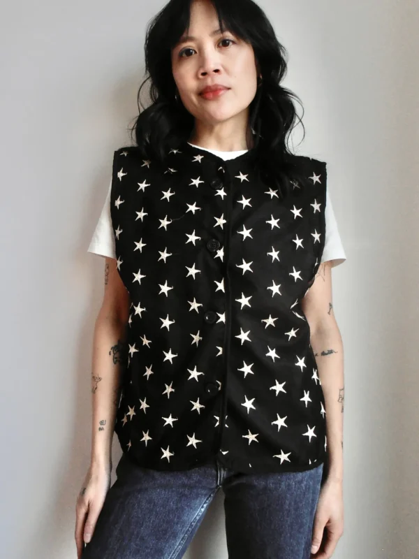 Front view of a black button-up vest with embroidered silver stars, made from sustainable deadstock fabric.