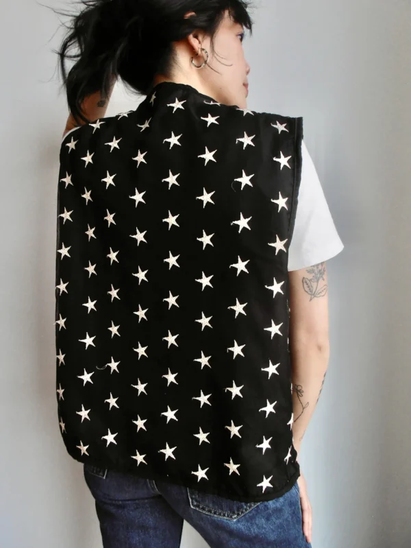 Backside of a black vest with embroidered silver stars, made from sustainable deadstock polyester fabric.