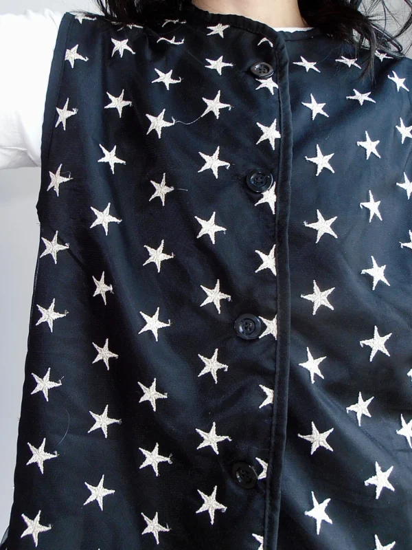 Close-up of a black vest with embroidered silver stars, made from sustainable deadstock polyester fabric.