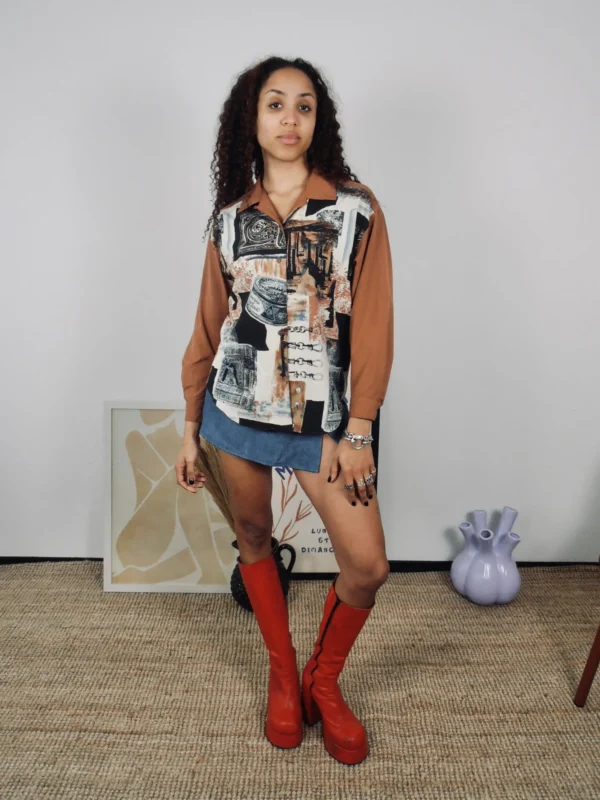 Model wearing a vintage tan and multicolour print blouse with denim skort and red boots.