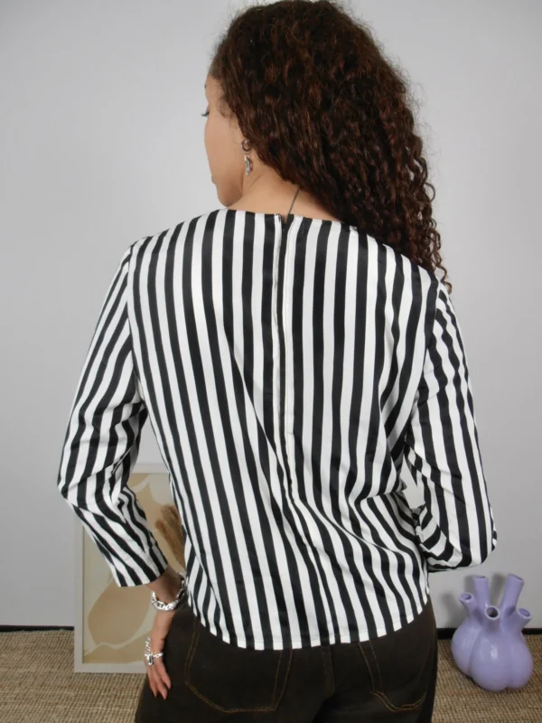 Back view of a vintage black and white striped blouse with side slit detail.
