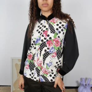 Front view of a vintage black polka-dot and multicolour floral print blouse with black collar and sleeves.
