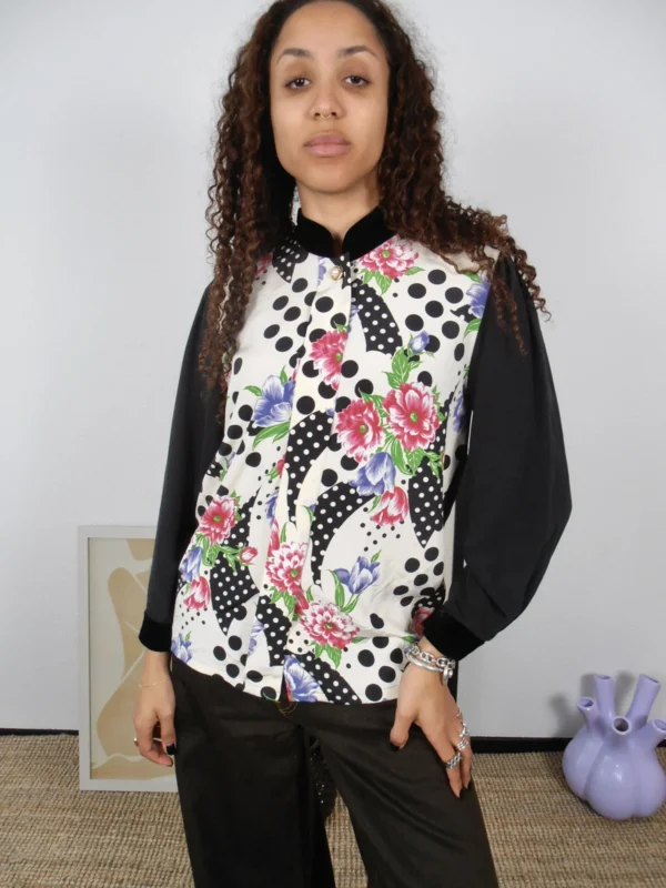 Front view of a vintage black polka-dot and multicolour floral print blouse with black collar and sleeves.