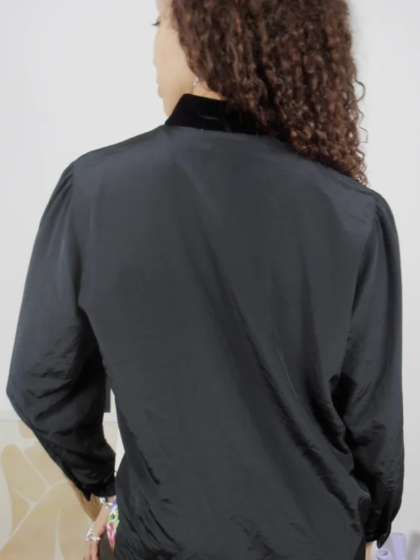 Back view of a vintage black polka-dot and multicolour floral print blouse with black collar and sleeves.