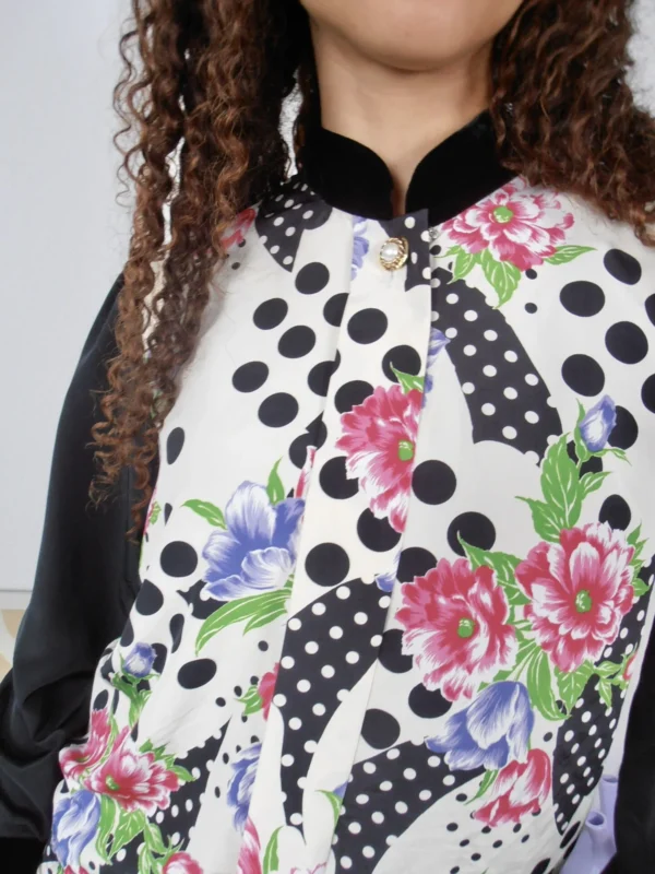 Close up of a vintage black polka-dot and multicolour floral print blouse with black mandarin collar and sleeves.